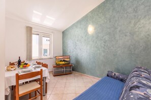 A room with a dining area, a television, and a bed.