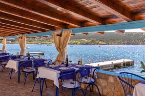 An outdoor dining area with tables and chairs, overlooking a body of water with boats. - Family Resort Santa Maria I Apartment 3, Stara Novalja, Croatia (Stara Novalja)
