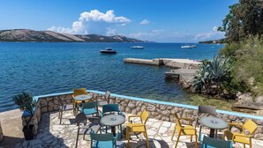 Une terrasse en pierre avec des sièges extérieurs et une vue sur la mer.