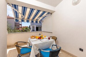Ein Balkon mit einem Frühstückstisch, ausgestattet mit Früchten und Saft, sowie Korbstühlen.