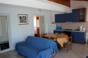 Un espace de vie compact comprenant un canapé, une table à manger et un coin cuisine.