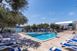 Área da piscina com espreguiçadeiras e vista para o mar.