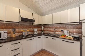 A modern kitchen with white cabinets, a microwave, a stove, and a sink.