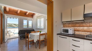 Une cuisine avec des meubles blancs, un four à micro-ondes et un coin repas comprenant une table et des chaises.