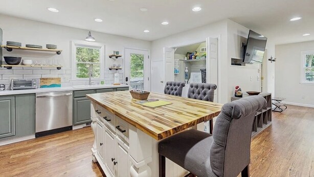 A modern kitchen with a wooden island, grey upholstered chairs, and built-in appliances. - Charming dog-friendly cottage near Blowing Rock with private hot tub, deck, BBQ (Blowing Rock)