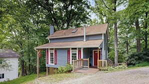A two-story house with a porch, a chimney, and a small deck. - Charming dog-friendly cottage near Blowing Rock with private hot tub, deck, BBQ (Blowing Rock)