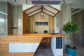 A reception desk with a wooden top and a potted plant to the right. - Fangtingshu Hostel (Zhangjiajie)