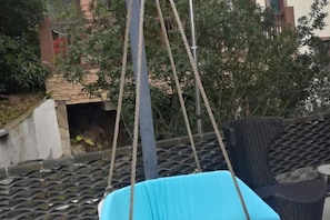 A blue swing chair suspended by ropes, a wicker chair, and a stone-tiled roof. - Fangtingshu Hostel (Zhangjiajie)