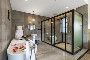 Un baño moderno con una bañera independiente, ducha con cerramiento de vidrio y un lavamanos con espejo.