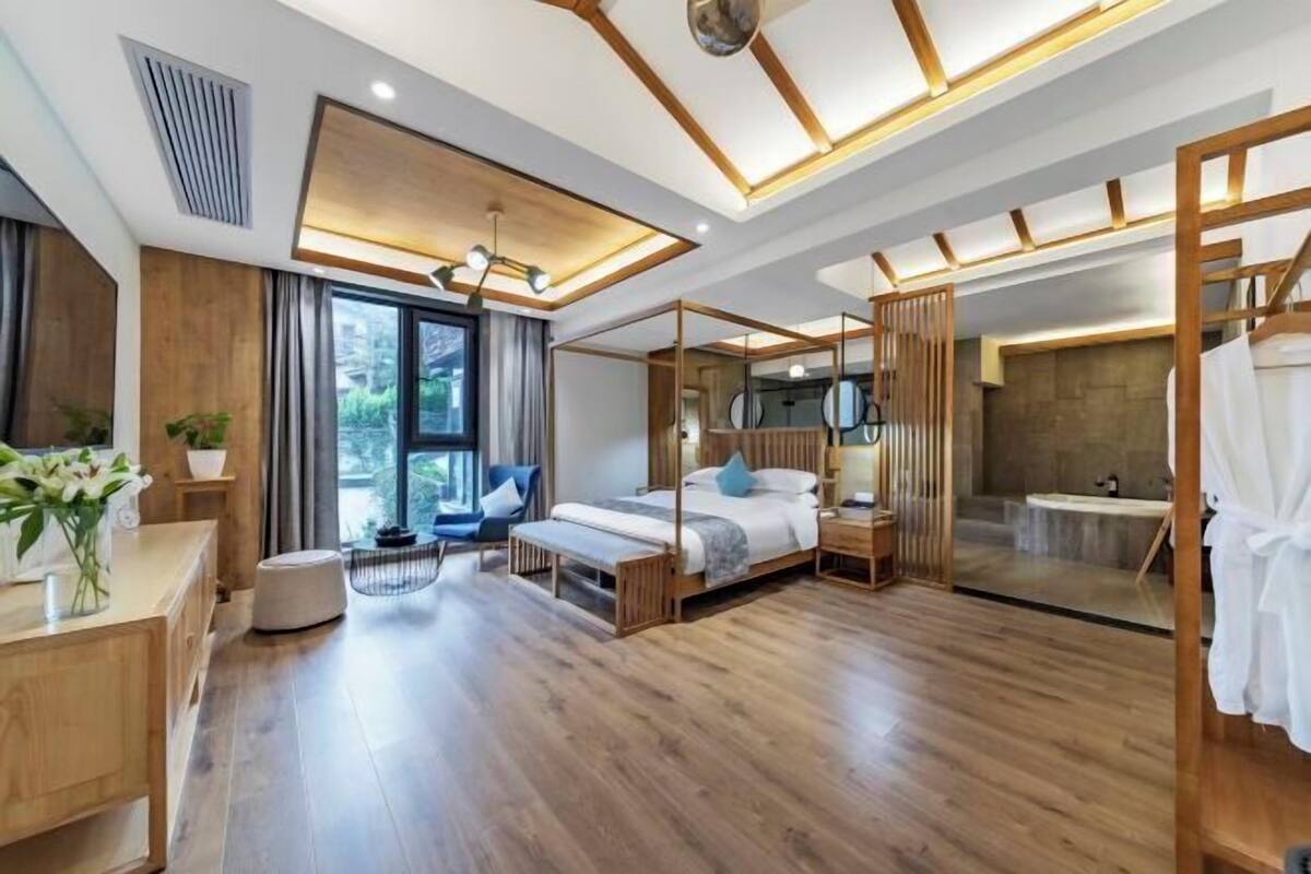 Un dormitorio moderno con una cama grande, mesitas de noche, un escritorio y un baño con bañera.