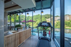 Een modern interieur met een loopband, zitplaatsen en grote ramen met uitzicht op groen.
