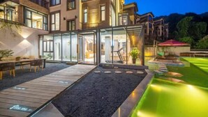 Un edificio moderno de varios pisos con fachada de vidrio, zona de estar al aire libre y jardín ajardinado.