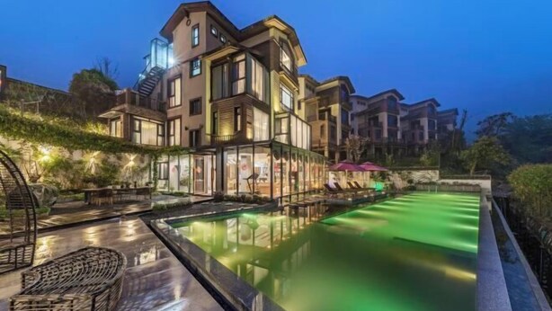Un hotel moderno con piscina, zona de estar exterior y área con paredes de vidrio.
