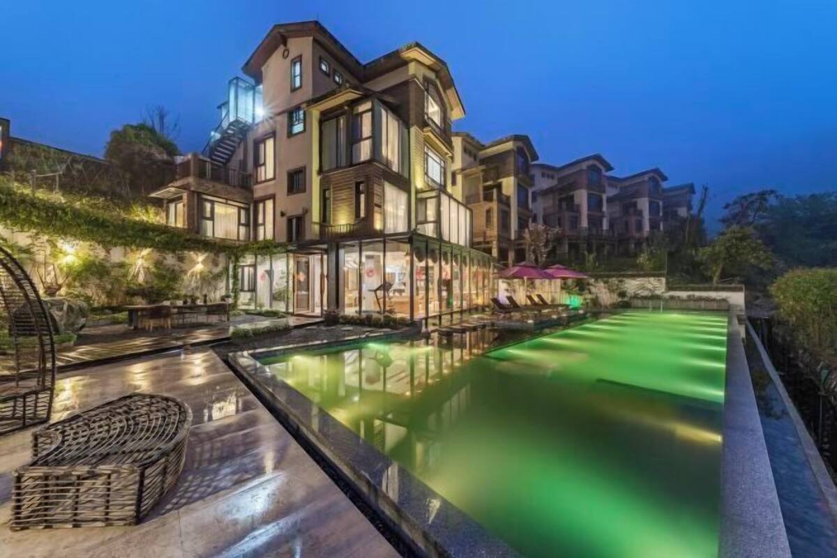 Un hotel moderno con piscina, zona de estar exterior y área con paredes de vidrio.