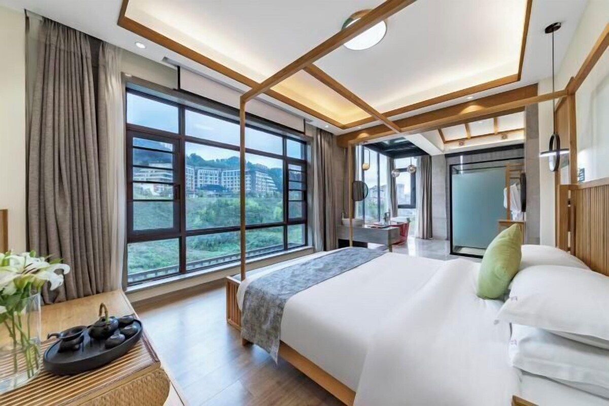 A modern hotel room with a large bed, a view of the city, and a balcony.