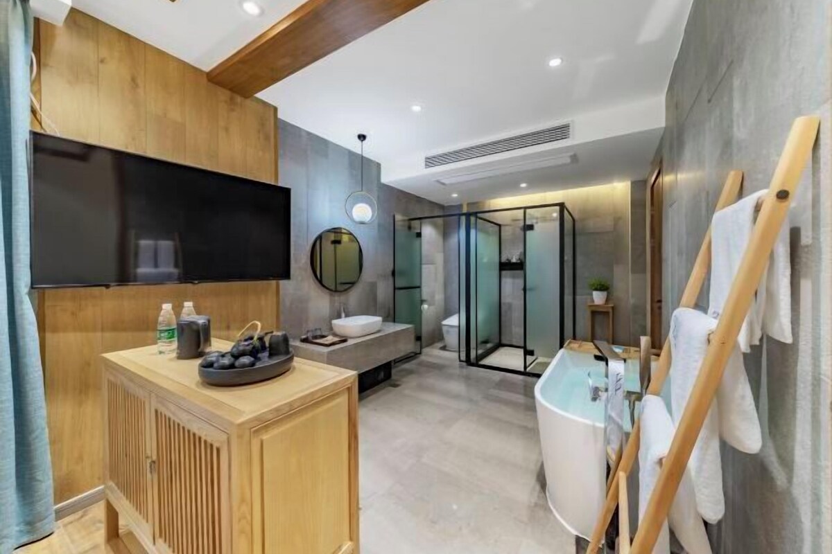 A modern bathroom with a wooden vanity, a large mirror, a bathtub, and a glass shower enclosure.