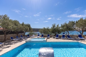En swimmingpool med liggestole og havudsigt.