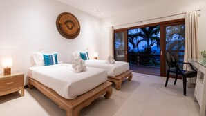 A hotel room with two beds, a large circular wall art piece, and a balcony with a view of palm trees.