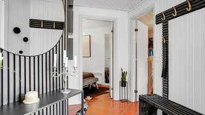 A modern interior with a curved mirror, a bench, a potted plant, and a doorway leading to another room.