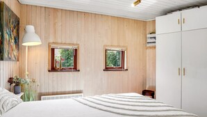 A bedroom with a bed, two windows, a white wardrobe, and a lamp.