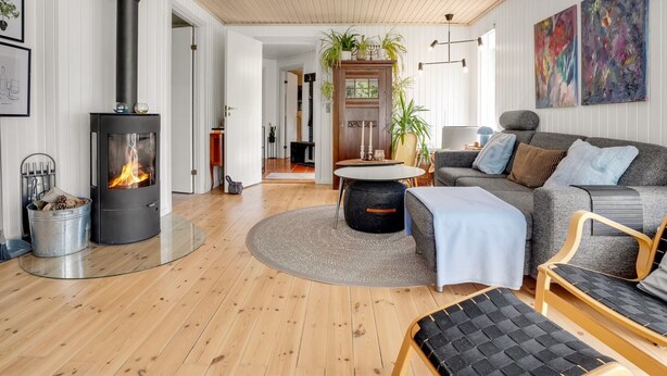 A modern living room with a wood-burning stove, a sofa, a coffee table, and a dining area.
