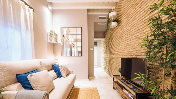 Een moderne woonkamer met een bank, een flatscreen televisie en een bakstenen muur.