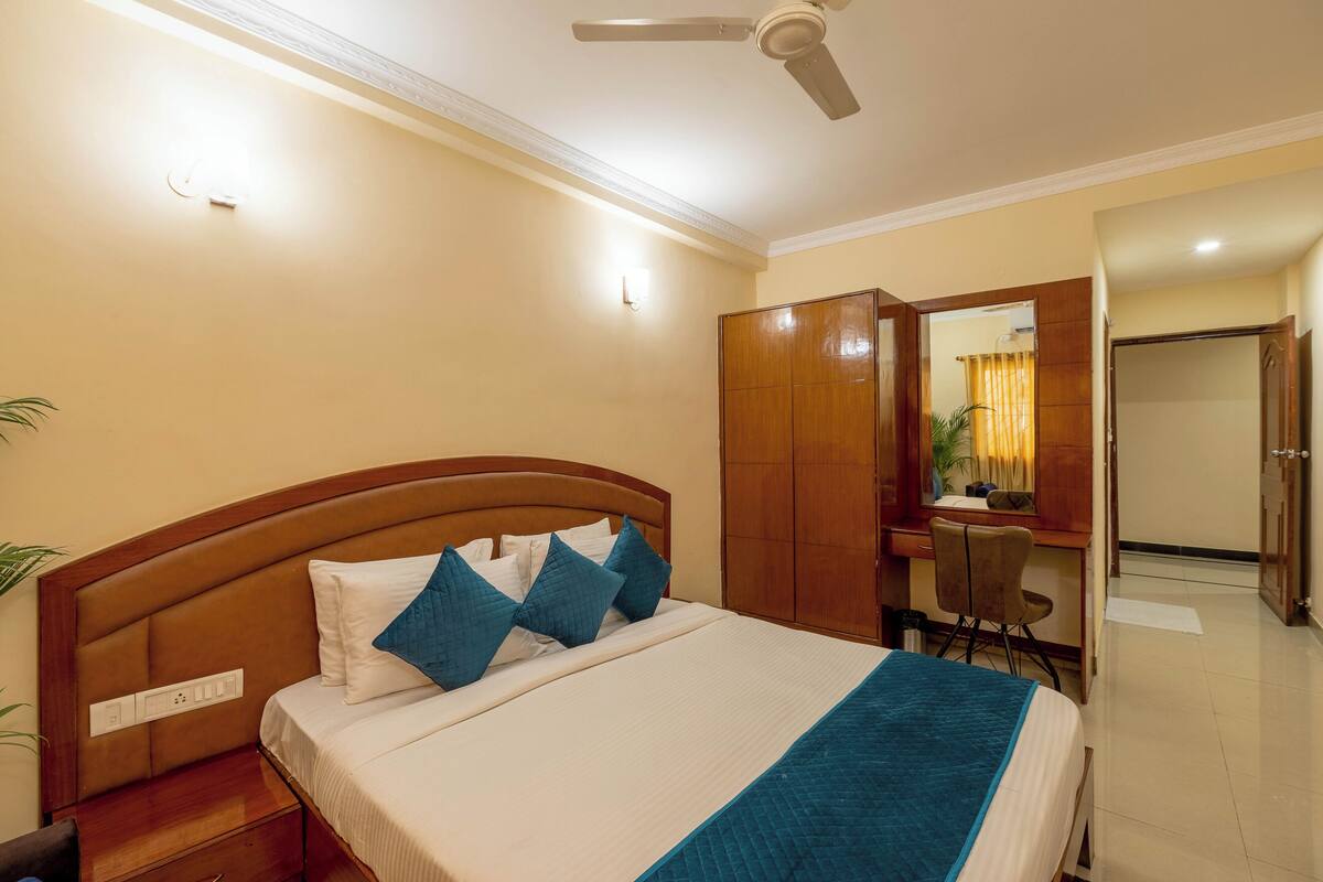 Una habitación de hotel con cama, escritorio, silla y armario.