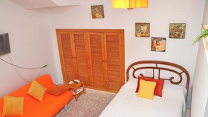 A bedroom with a bed, a sofa, a wooden wardrobe, and artwork on the walls. - El Rinconcito de Pepa I,close to the beach (Conil de la Fra.)