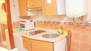 A compact kitchen with a microwave, sink, and a water heater. - El Rinconcito de Pepa I,close to the beach (Conil de la Fra.)