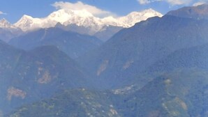 A mountain range with snow-capped peaks and dense forested valleys. - Divsai Retreat (Gyalshing)