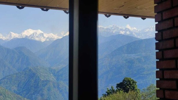 A mountain view from a window with a brick wall and a wooden ceiling. - Divsai Retreat (Gyalshing)