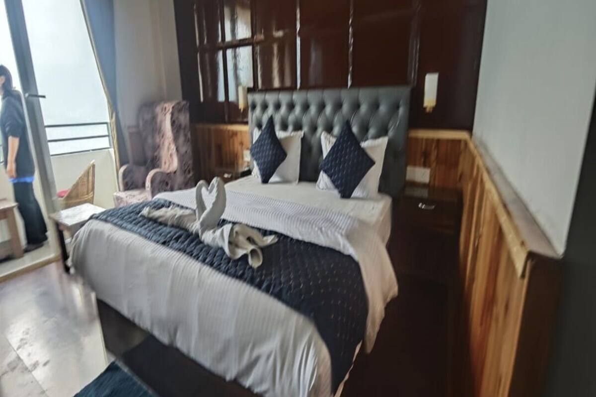 A bedroom with a large bed, a chair, and a wooden headboard.