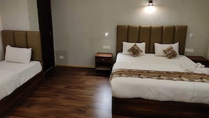 A hotel room with a large bed, a smaller bed, a nightstand, and a wall-mounted light fixture. - Divsai Retreat (Gyalshing)