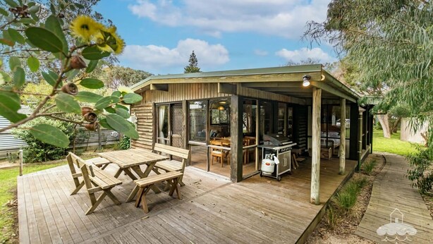 A wooden cabin with a deck, a dining area, and a kitchen. - Sandy Point Log Cabin (Sandy Point)