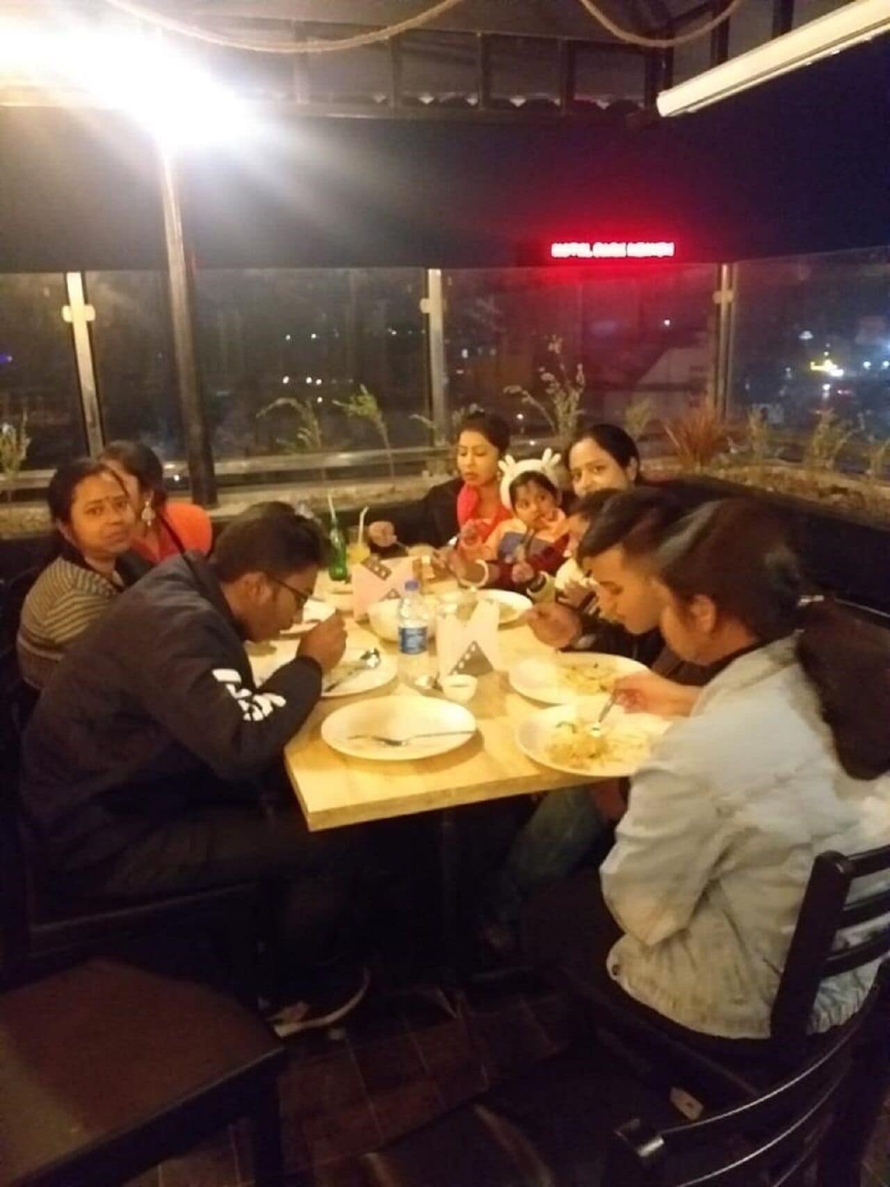 A group of people dining at a table with a view of the city at night.