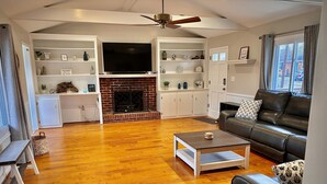 Un salón amplio con chimenea, televisor de pantalla plana y sofá de cuero.