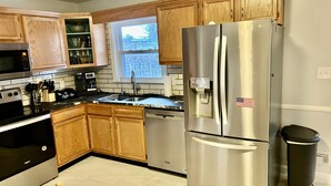 Una cocina moderna con armarios de madera, electrodomésticos de acero inoxidable y un ventanal que proporciona luz natural.