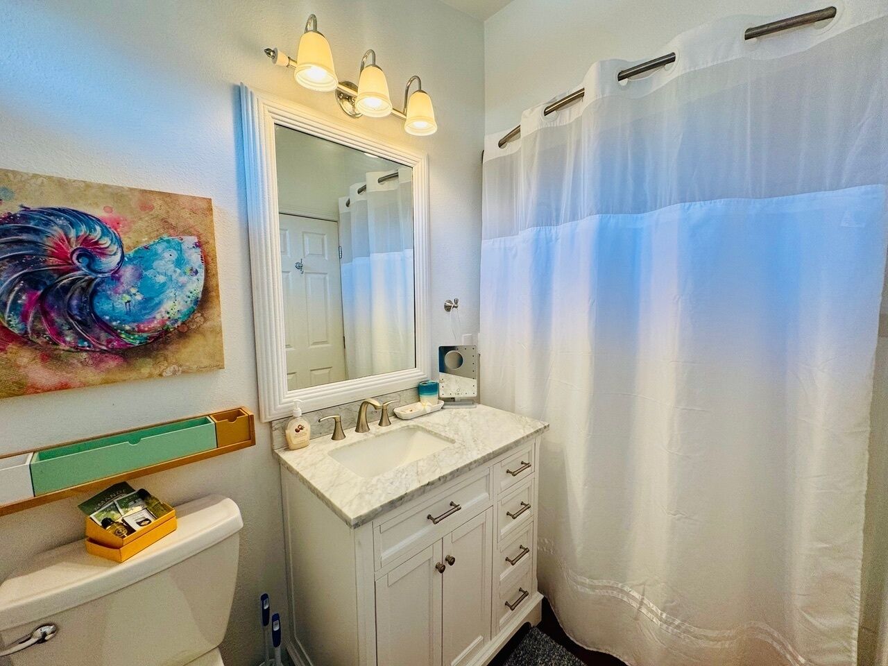 Une salle de bain avec un lavabo blanc, un meuble-lavabo et un rideau de douche.