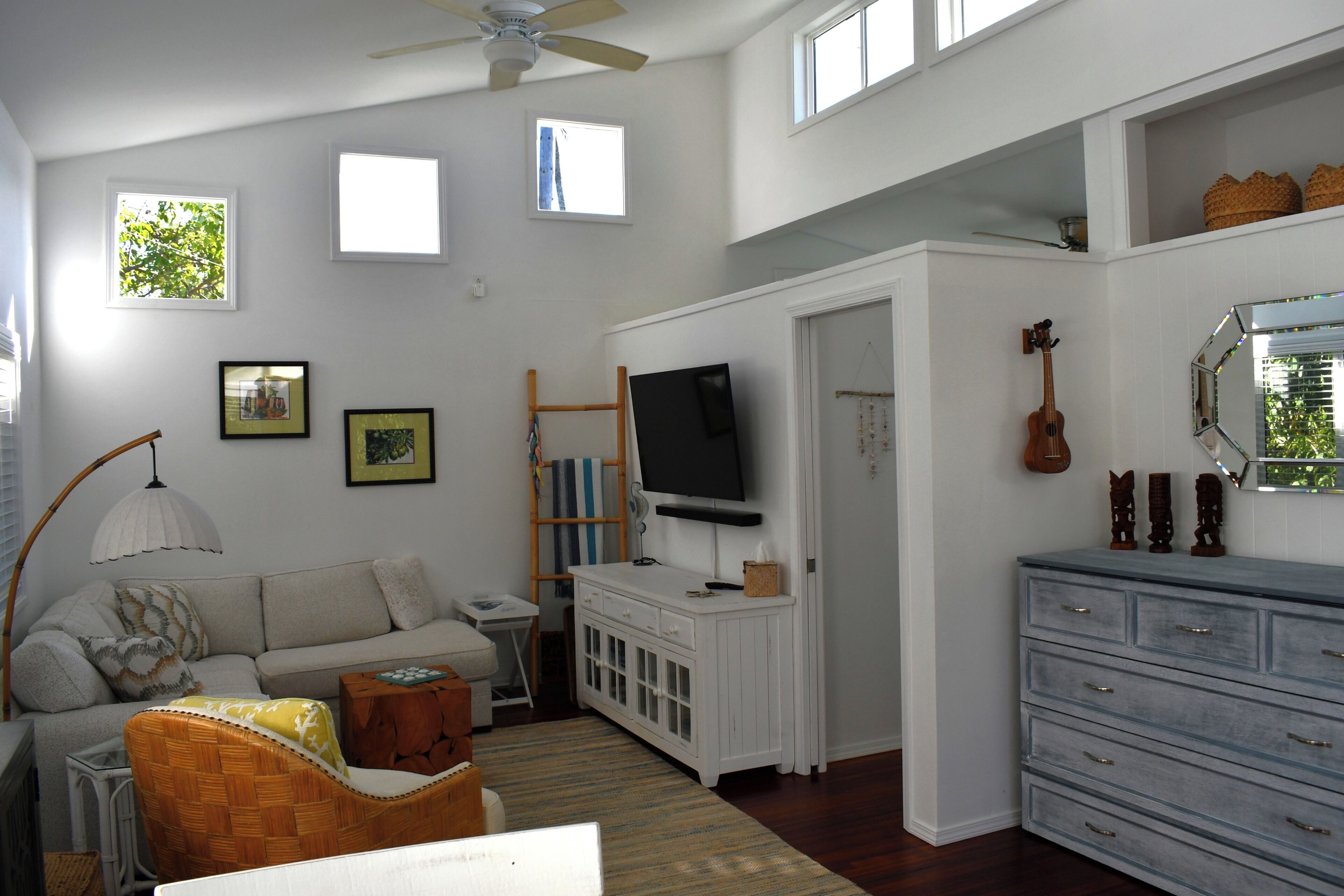 A living room with a sofa, a television, a guitar, and a cabinet.