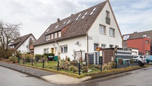 Ein Wohnhaus mit Satteldach, Satellitenschüssel und einem umzäunten Garten.