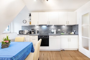 Eine moderne Küche mit weißen Schränken, einem schwarzen Backofen und einem blauen Tisch mit einer Pflanze.