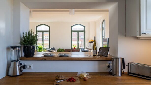 Una cocina con encimera de madera, una licuadora, un tostador y una planta en maceta.