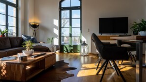 Una sala de estar moderna con sofá, mesa de centro, televisor y comedor.