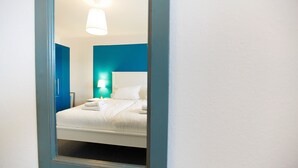 Ein Schlafzimmer mit Bett, Nachttisch, Lampe und Spiegel.