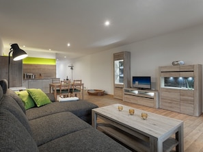 Una sala de estar moderna con sofá, comedor, televisor y mueble.