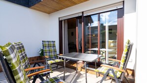Un patio con tavolo e sedie, una porta scorrevole in vetro e vista sull'esterno.