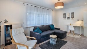 Ein modernes Wohnzimmer mit einer Couch, einem Sessel und einem Schreibtisch mit Stuhl.