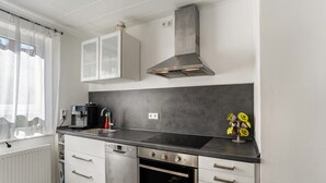 Eine moderne Küche mit weißen Schränken, einer Edelstahl-Dunstesse, einem eingebauten Backofen und einer schwarzen Arbeitsplatte.