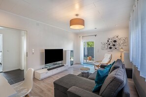 Un salon moderne avec un téléviseur à écran plat, un canapé, une table à manger et une chaise.
