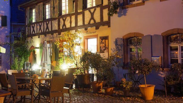 A traditional European building with a restaurant sign, outdoor seating, and potted plants. - Weissburgunder Superior Apartment 52 sqm, City View, up to 4 Guests, Optional Breakfast, 3D Tour (Vogtsburg)